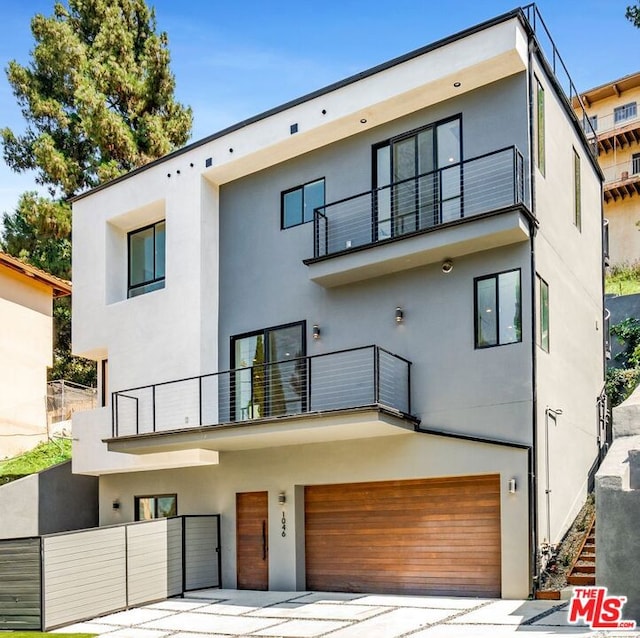 rear view of property featuring a balcony and a garage