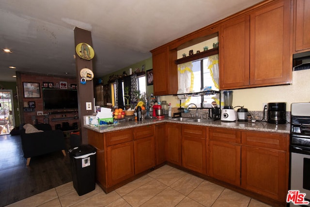 kitchen featuring light stone countertops, light tile patterned floors, ventilation hood, gas range, and sink