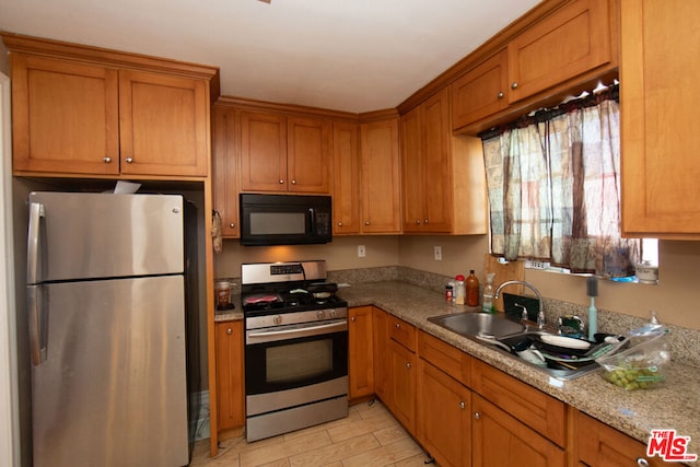 kitchen featuring appliances with stainless steel finishes, sink, and light stone counters