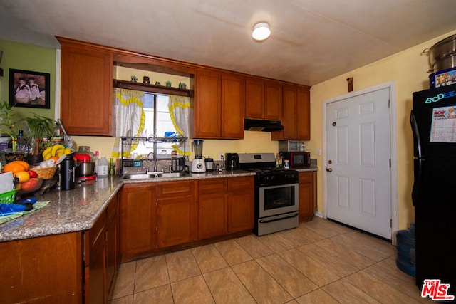 kitchen featuring black appliances, light stone counters, light tile patterned floors, and sink