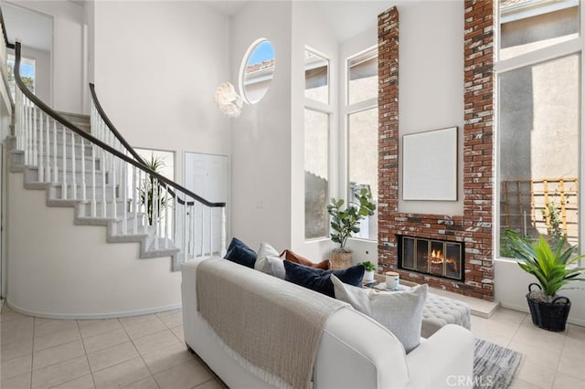 tiled living room with a wealth of natural light, a towering ceiling, and a brick fireplace