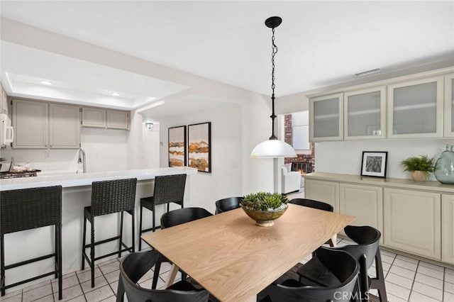 tiled dining area featuring a raised ceiling and sink