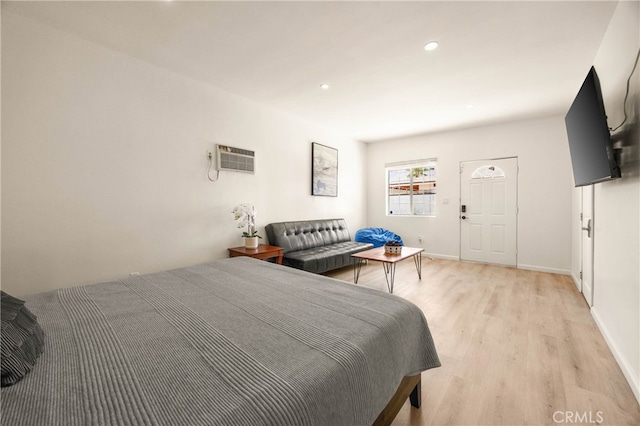 bedroom with light wood-type flooring and a wall mounted AC