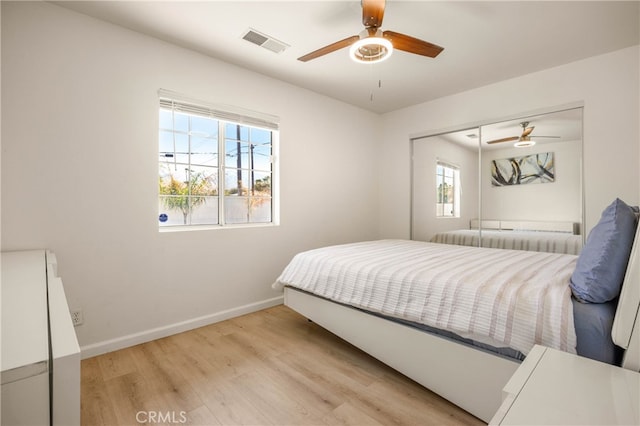 bedroom featuring multiple windows, light wood-type flooring, ceiling fan, and a closet