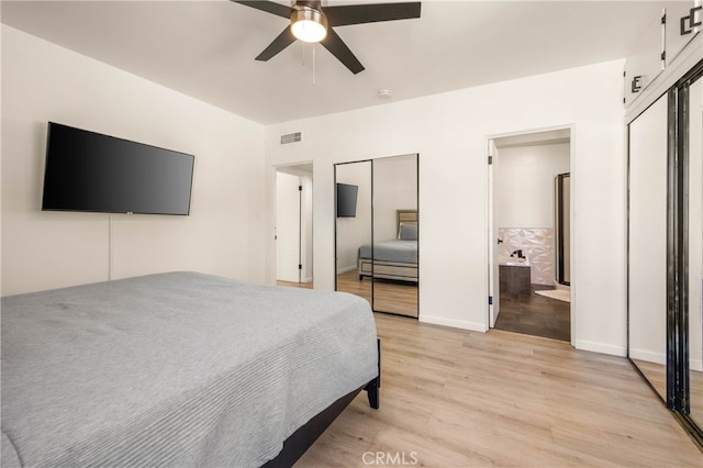 bedroom with ceiling fan, light wood-type flooring, and two closets