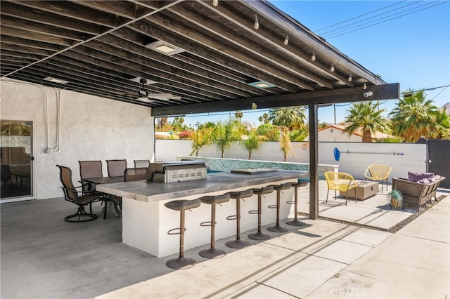 view of patio / terrace featuring ceiling fan, an outdoor kitchen, and a bar