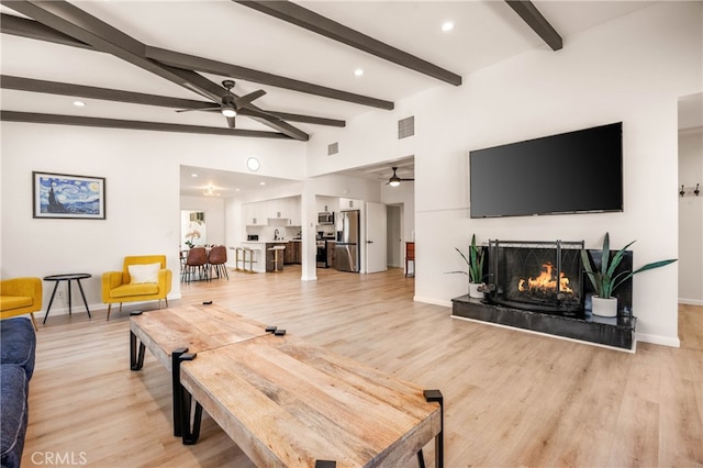 living room with a fireplace, lofted ceiling with beams, and light hardwood / wood-style flooring