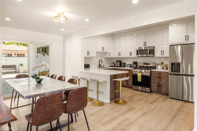 kitchen with light hardwood / wood-style floors, sink, stainless steel appliances, and white cabinets