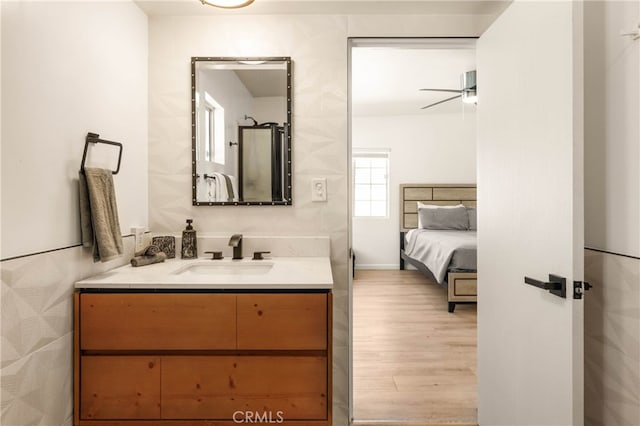 bathroom featuring wood-type flooring, vanity, an enclosed shower, and ceiling fan