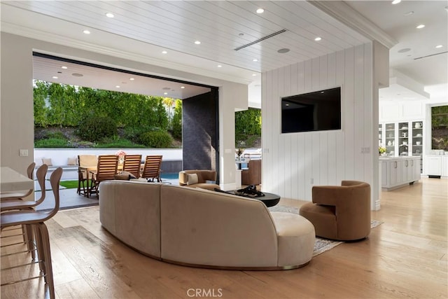 living room featuring wooden walls, light hardwood / wood-style flooring, and ornamental molding