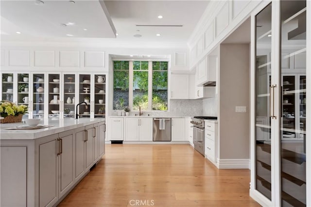 kitchen featuring backsplash, white cabinetry, stainless steel appliances, and light wood-type flooring