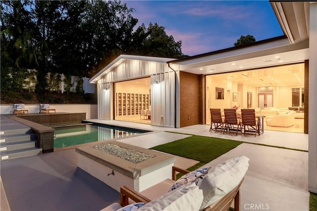 exterior space featuring a patio area, an outdoor living space with a fire pit, and exterior kitchen