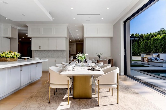 dining space with crown molding and light hardwood / wood-style flooring