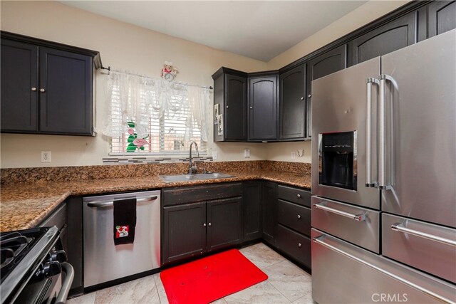 kitchen featuring appliances with stainless steel finishes, dark stone countertops, and sink