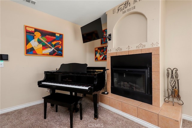 miscellaneous room with a tiled fireplace and carpet