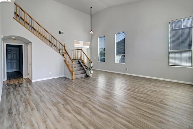 unfurnished living room featuring light wood-type flooring, high vaulted ceiling, and plenty of natural light