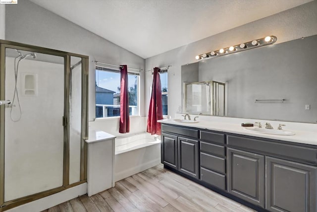 bathroom with plus walk in shower, hardwood / wood-style floors, vanity, and lofted ceiling