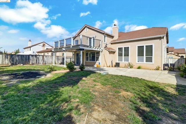 rear view of property with a yard, a patio, and a balcony