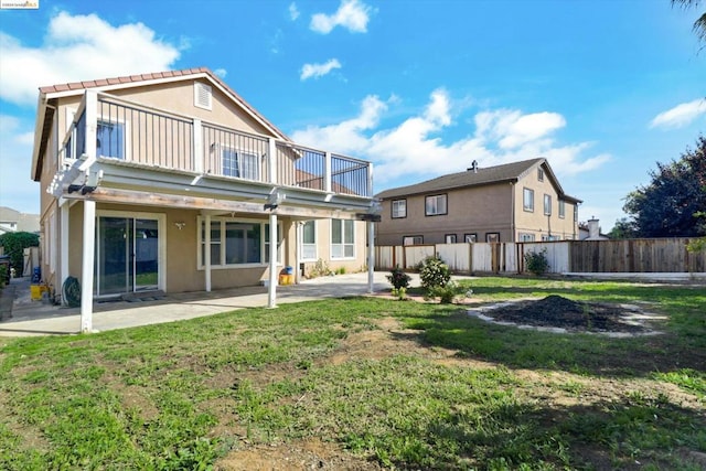 rear view of house with a patio, a balcony, and a lawn