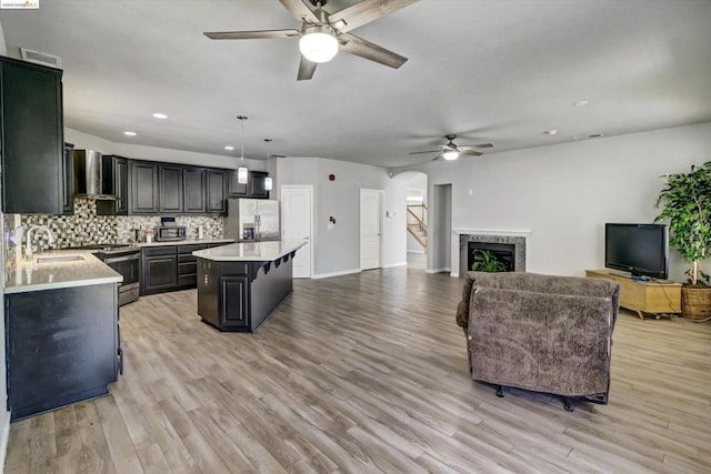 kitchen featuring a center island, hanging light fixtures, light wood-type flooring, and appliances with stainless steel finishes