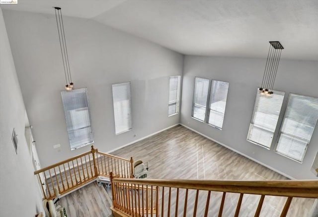 stairway featuring hardwood / wood-style floors and high vaulted ceiling