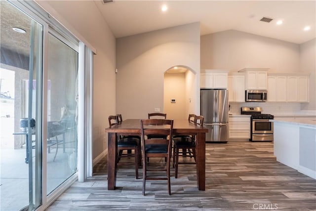 dining room featuring dark wood-type flooring and high vaulted ceiling