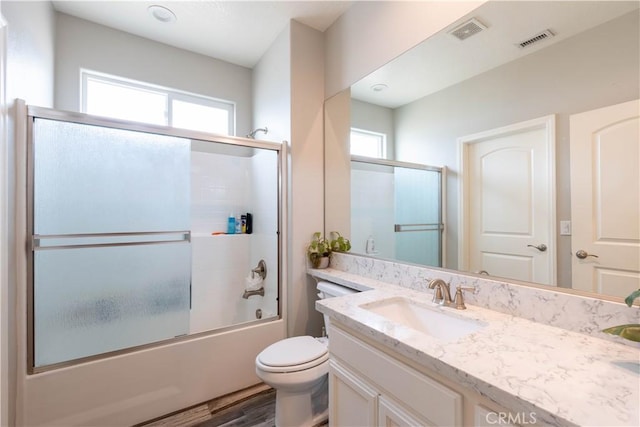 full bathroom with vanity, plenty of natural light, enclosed tub / shower combo, and toilet