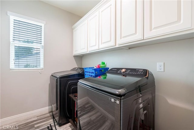 laundry room featuring cabinets, independent washer and dryer, and light hardwood / wood-style flooring