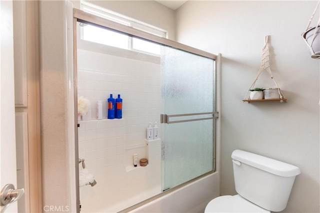 bathroom featuring enclosed tub / shower combo and toilet