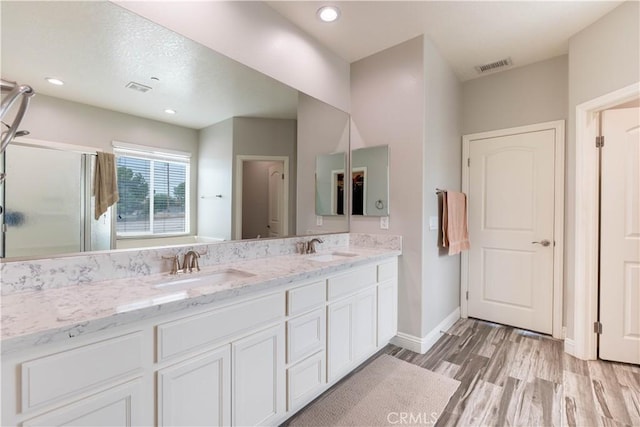 bathroom with wood-type flooring, vanity, and walk in shower