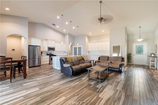 living room with ceiling fan, light hardwood / wood-style floors, and high vaulted ceiling