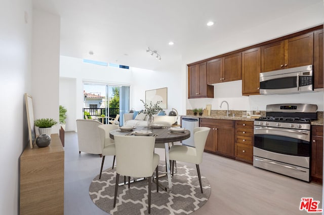 kitchen featuring light stone counters, appliances with stainless steel finishes, sink, and light hardwood / wood-style flooring