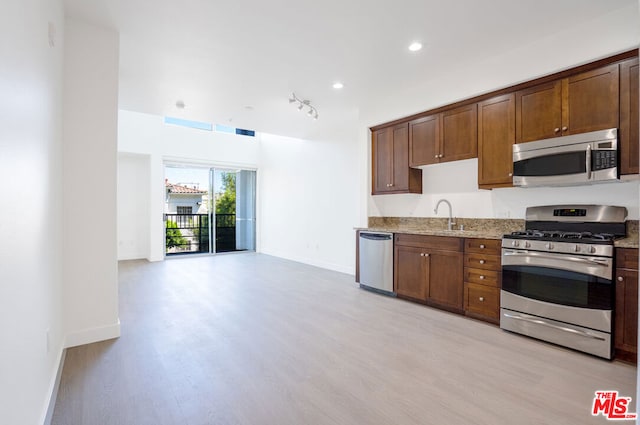 kitchen with light wood-type flooring, light stone countertops, sink, and stainless steel appliances