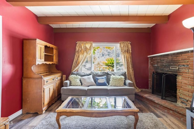 living room featuring beamed ceiling, a brick fireplace, and dark wood-type flooring