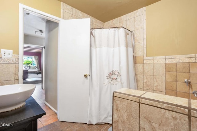 bathroom with tile patterned floors, vanity, tile walls, and walk in shower