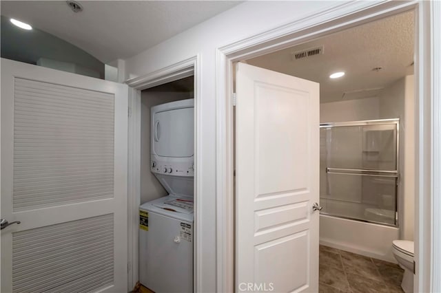 laundry area featuring stacked washer and clothes dryer and tile patterned flooring