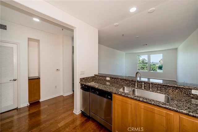 kitchen featuring dark stone countertops, dishwasher, dark wood-type flooring, and sink