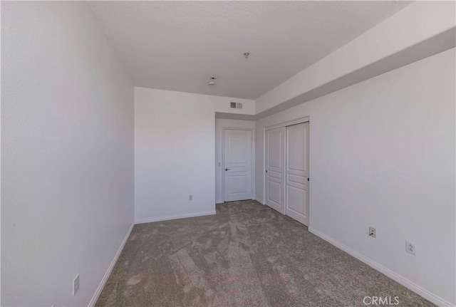 unfurnished bedroom with dark carpet and a closet