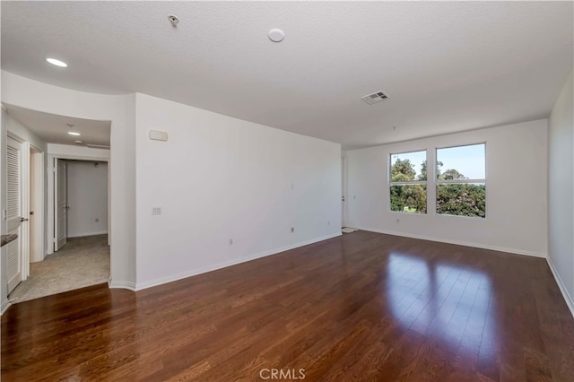 spare room with a textured ceiling and dark wood-type flooring