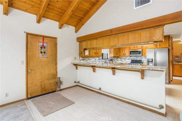 kitchen featuring a breakfast bar, decorative backsplash, kitchen peninsula, and appliances with stainless steel finishes