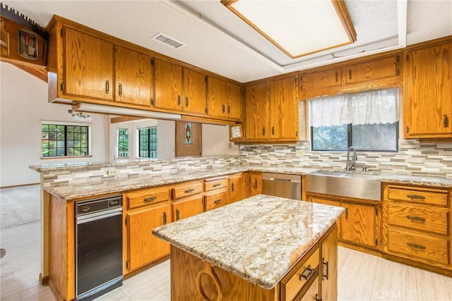 kitchen with kitchen peninsula, dishwasher, a kitchen island, and a healthy amount of sunlight