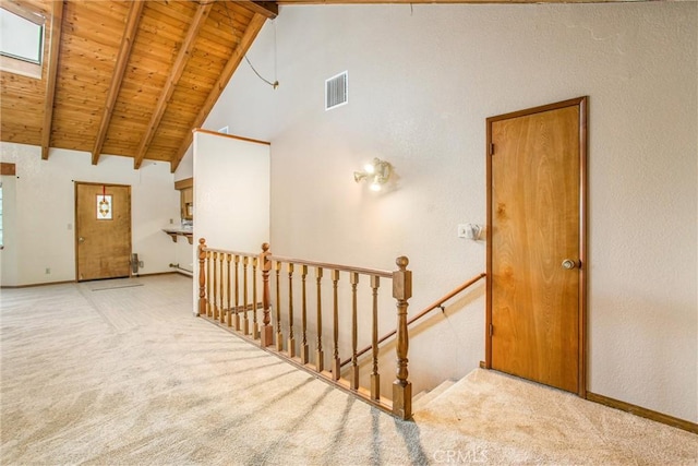 interior space with a skylight, beamed ceiling, high vaulted ceiling, carpet floors, and wood ceiling