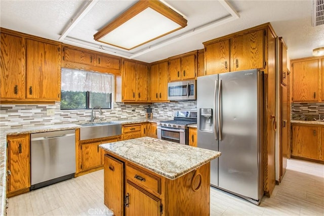 kitchen featuring decorative backsplash, appliances with stainless steel finishes, a center island, and sink