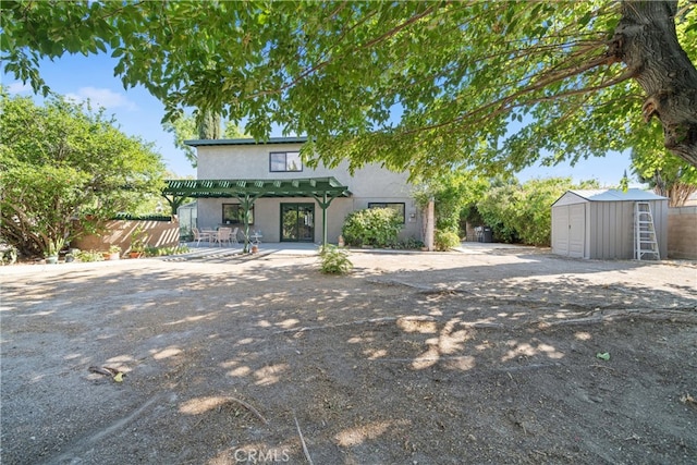 view of front facade with a storage shed, a pergola, and a patio area