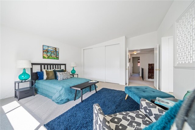 carpeted bedroom with a closet and lofted ceiling