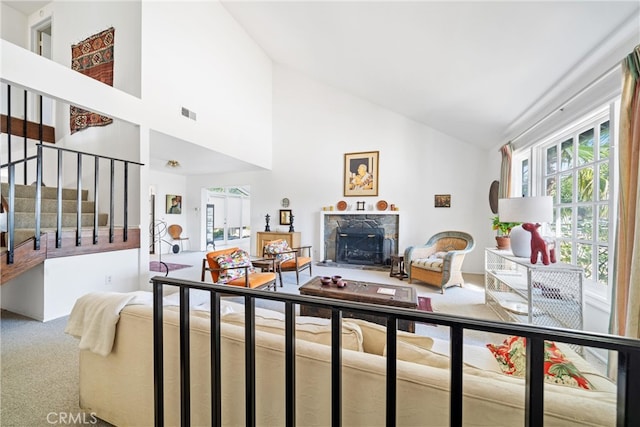 carpeted living room featuring high vaulted ceiling and a premium fireplace