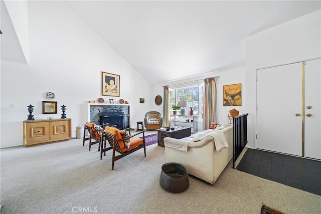 carpeted living room with a stone fireplace and high vaulted ceiling