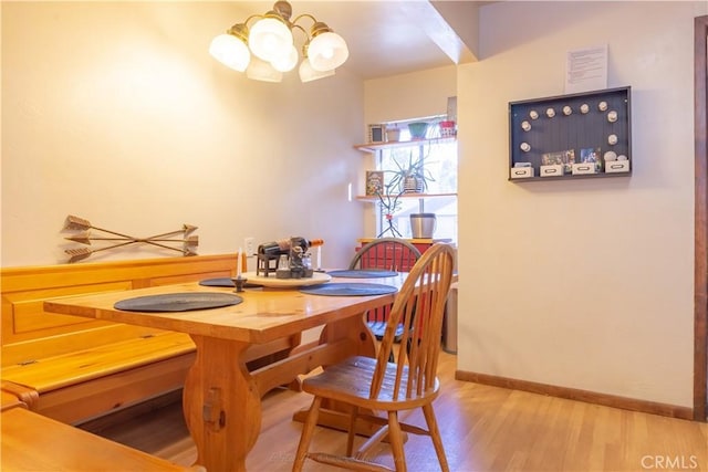 dining space featuring a chandelier, baseboards, and wood finished floors