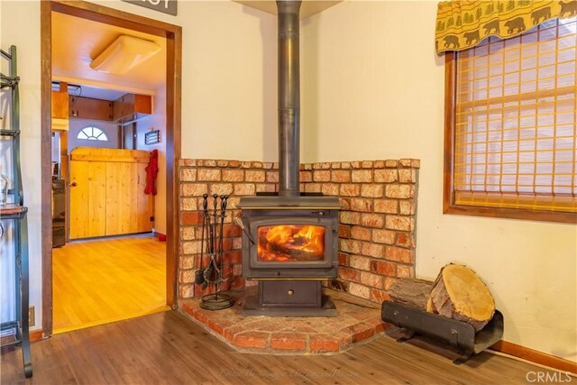 interior details featuring a wood stove, baseboards, and wood finished floors