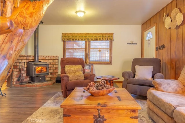 living room with wooden walls, wood finished floors, and a wood stove